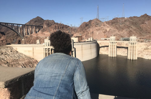 Ashley a.k.a girlwithherviews at the hoover dam overlooking the water from a tourist viewpoint