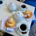 An Italian Breakfast of sugar covered broiche buns with two teapots and two teacups filled with black tea